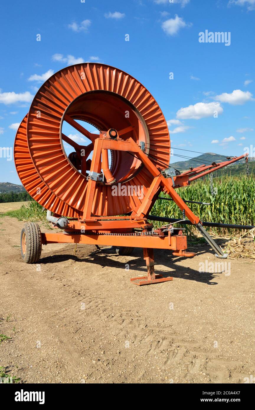 Agricultural irrigation system with a big hose reel in a cornfield during summer. Stock Photo
