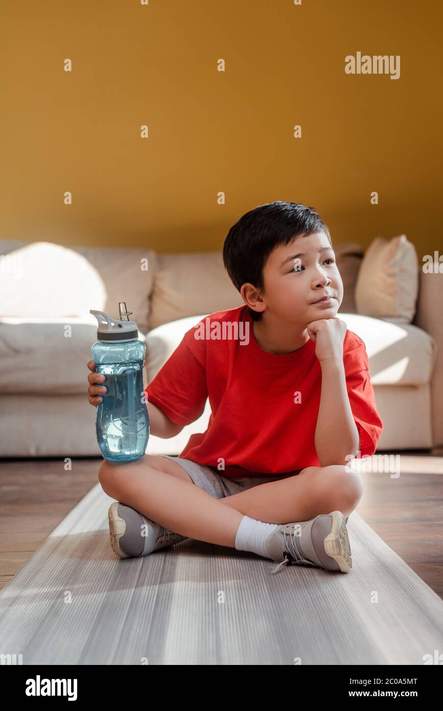 https://c8.alamy.com/comp/2C0A5MT/thoughtful-sportive-asian-boy-with-sports-bottle-sitting-on-fitness-mat-at-home-during-quarantine-2C0A5MT.jpg
