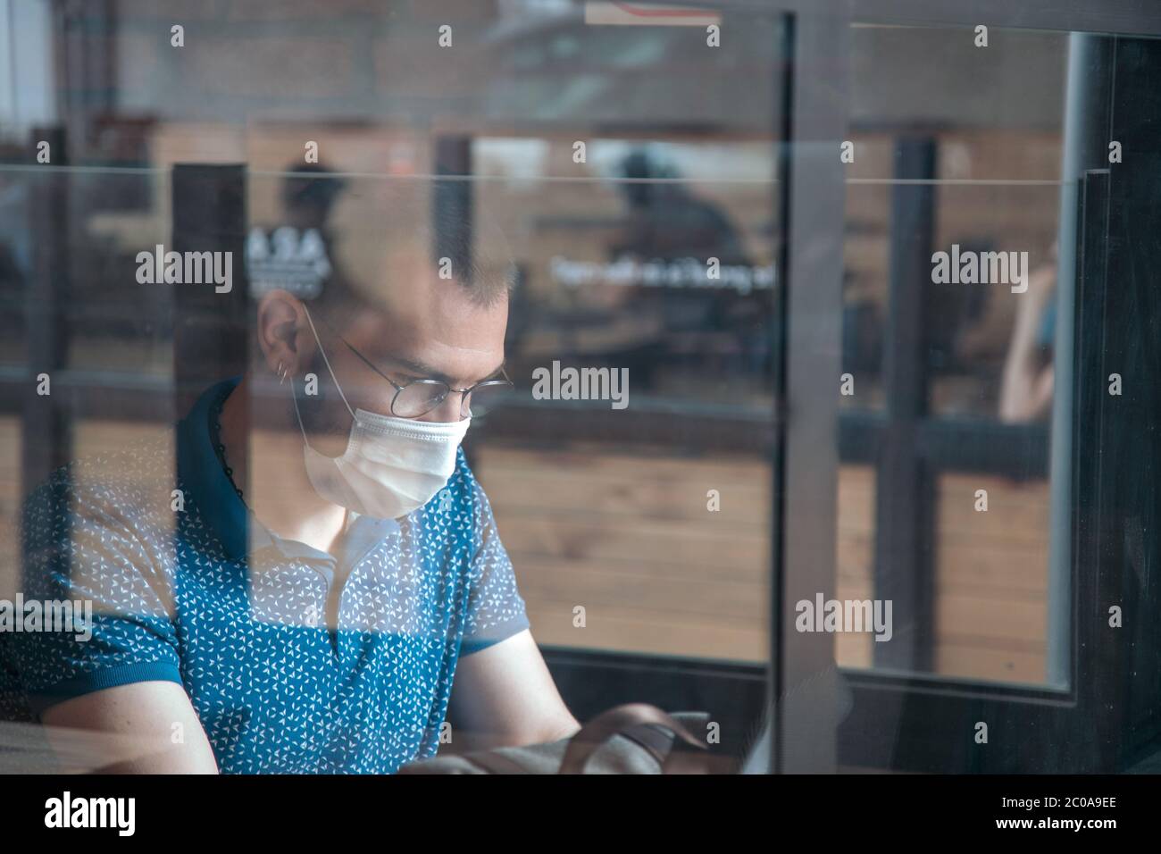 Young man works in a public cafe with protective mask Stock Photo