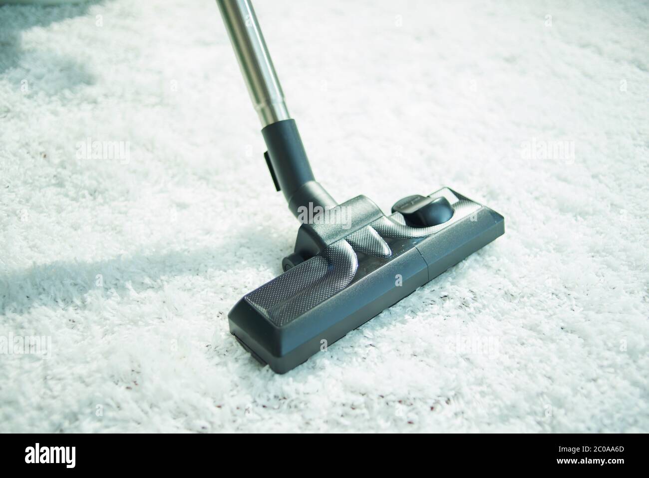 Closeup on vacuum cleaner vacuuming white fluffy carpet. Stock Photo