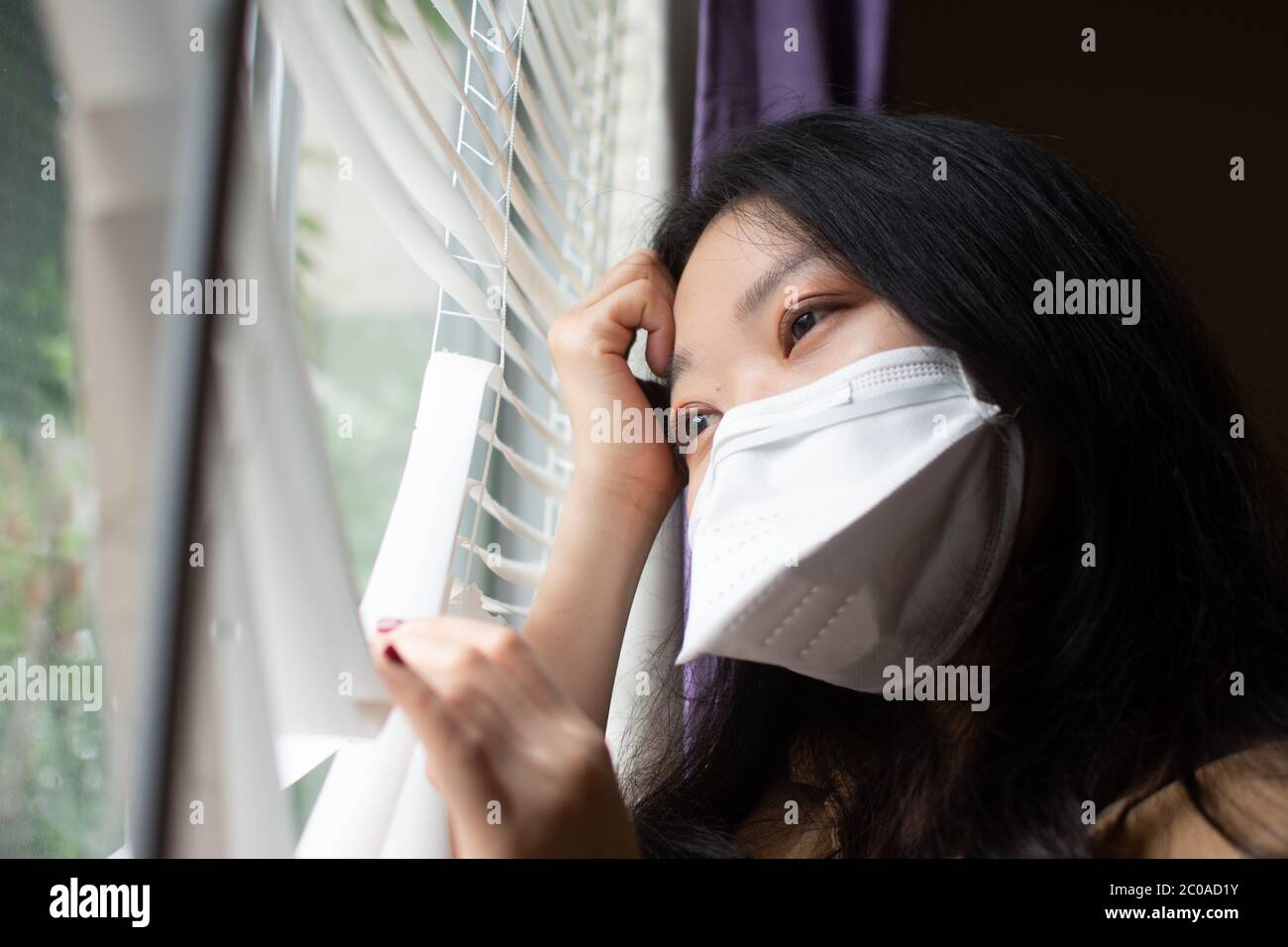 COVID-19 Pandemic Coronavirus Asian Woman Daydreaming Looking Outside During Stay At Home Order Stock Photo