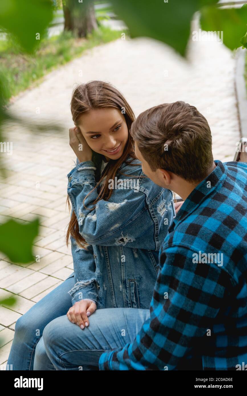 selective focus of attractive girl touching hair while flirting with ...