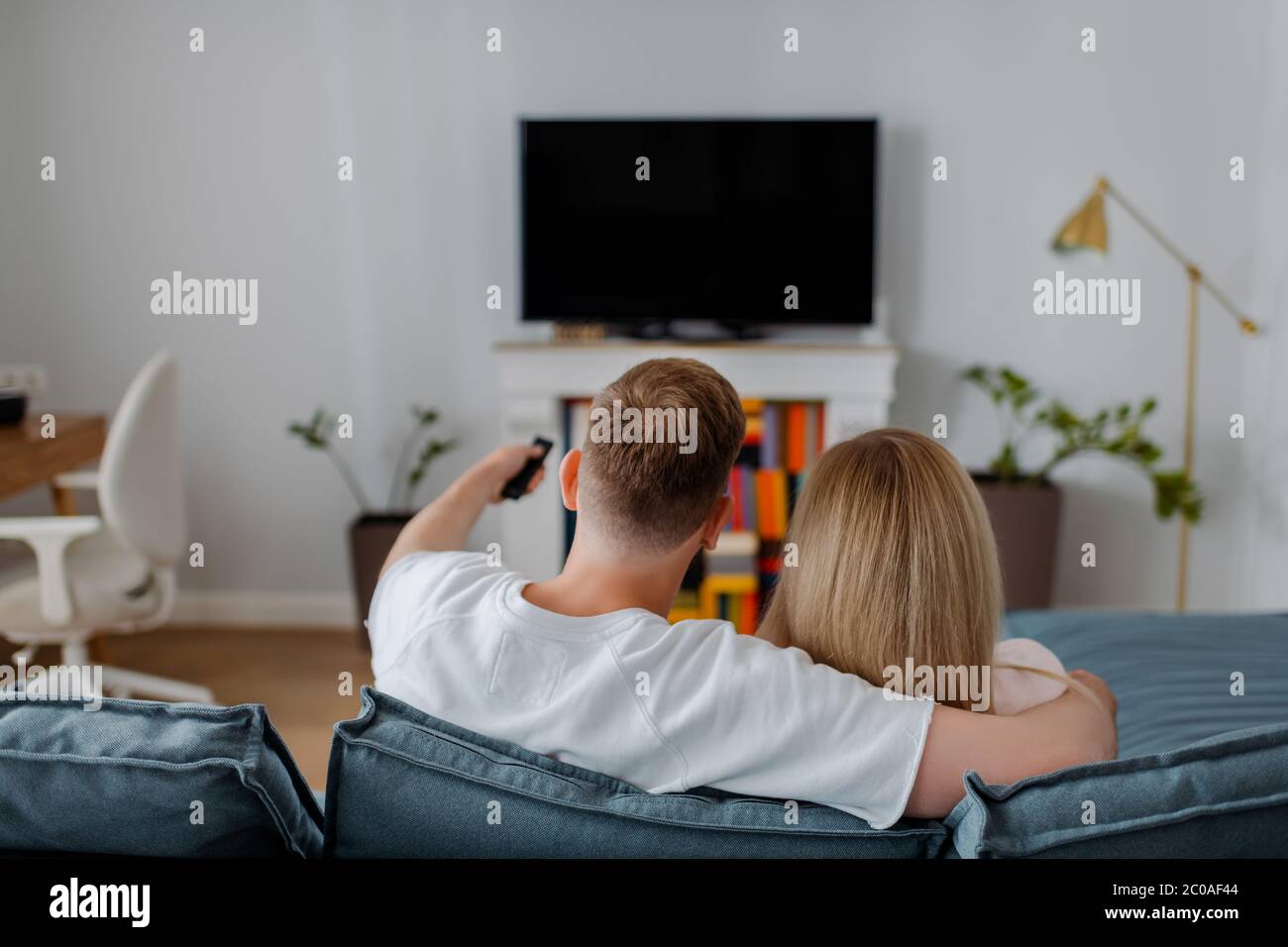back view of man and woman sitting near flat panel tv with blank screen Stock Photo