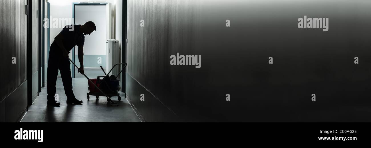 Silhouette Of A Male Janitor Cleaning Corridor Stock Photo