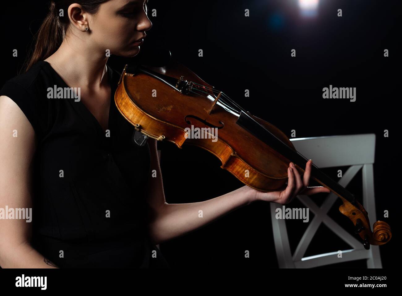 beautiful female musician playing on violin on black with back light ...