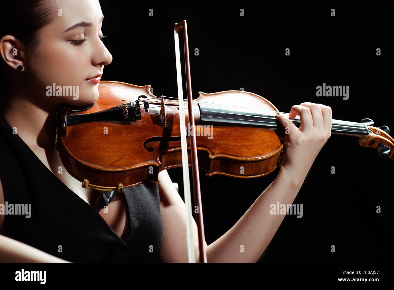 attractive female musician playing symphony on violin isolated on black ...