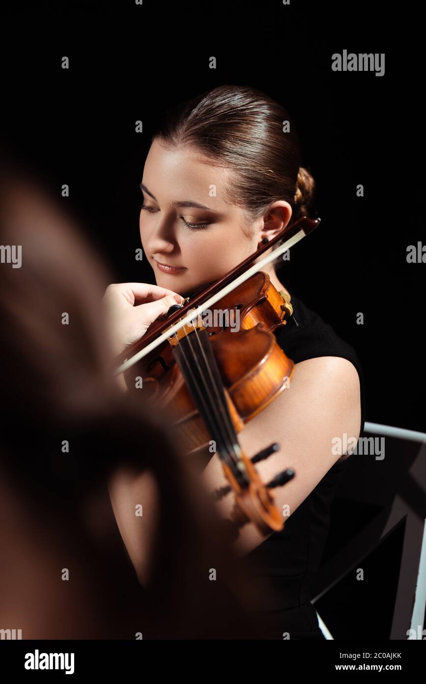 attractive female musician playing on violin on dark stage Stock Photo ...