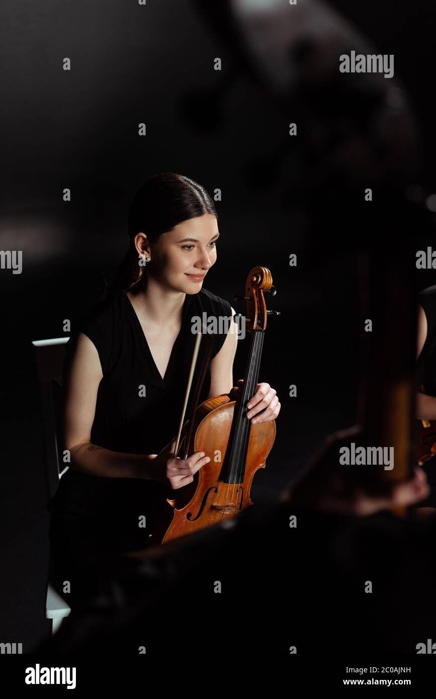 happy female musician holding violin on dark stage Stock Photo - Alamy