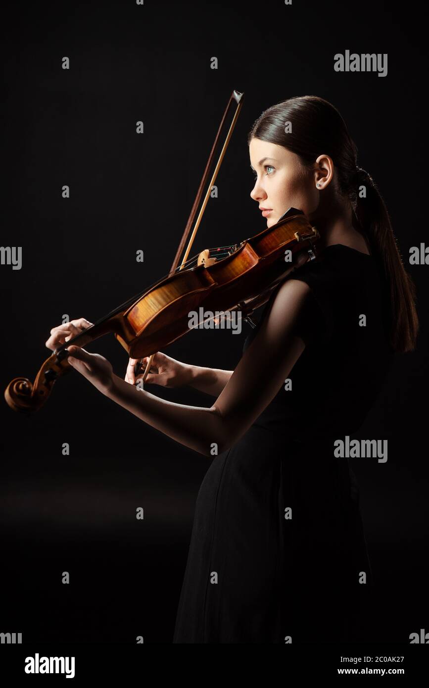 attractive female musician playing on violin isolated on black Stock ...