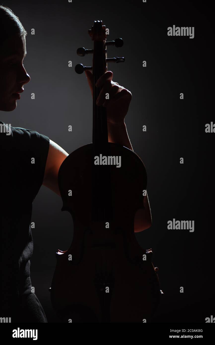 silhouette of female musician holding violin on dark stage Stock Photo ...