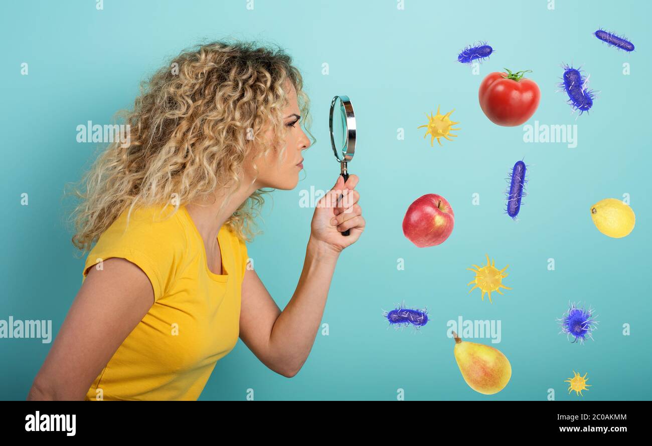 Girl is distrustful about contagion of bacteria on food. Cyan background Stock Photo