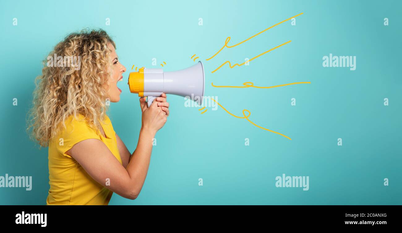 Woman screams with loudspeaker. angry expression. cyan background Stock Photo
