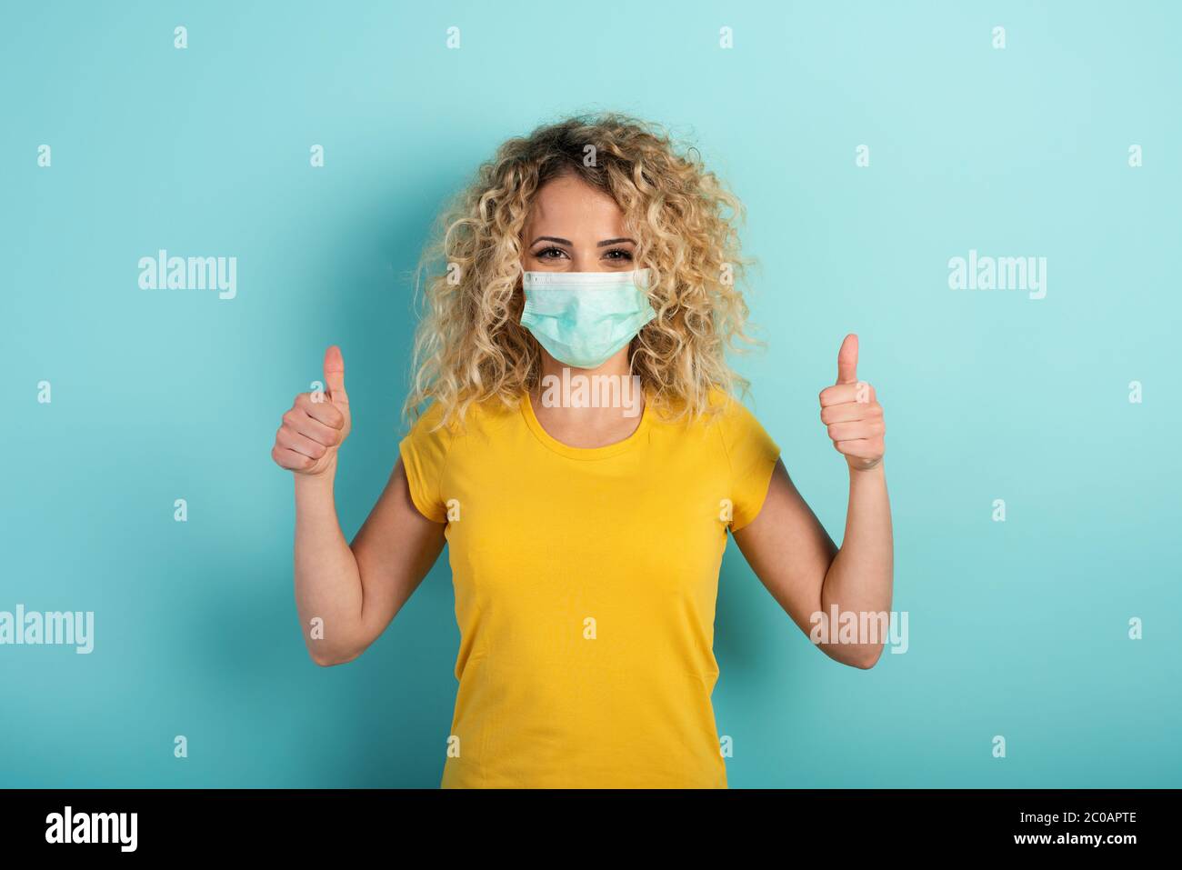 Girl is optimistic about the defeat of covid 19 coronavirus. Cyan background Stock Photo