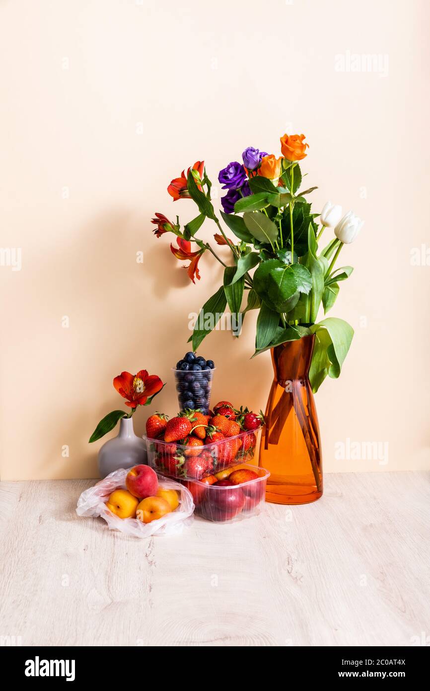 floral and fruit composition with bouquet in vase and summer fruits on  wooden surface on beige background Stock Photo - Alamy