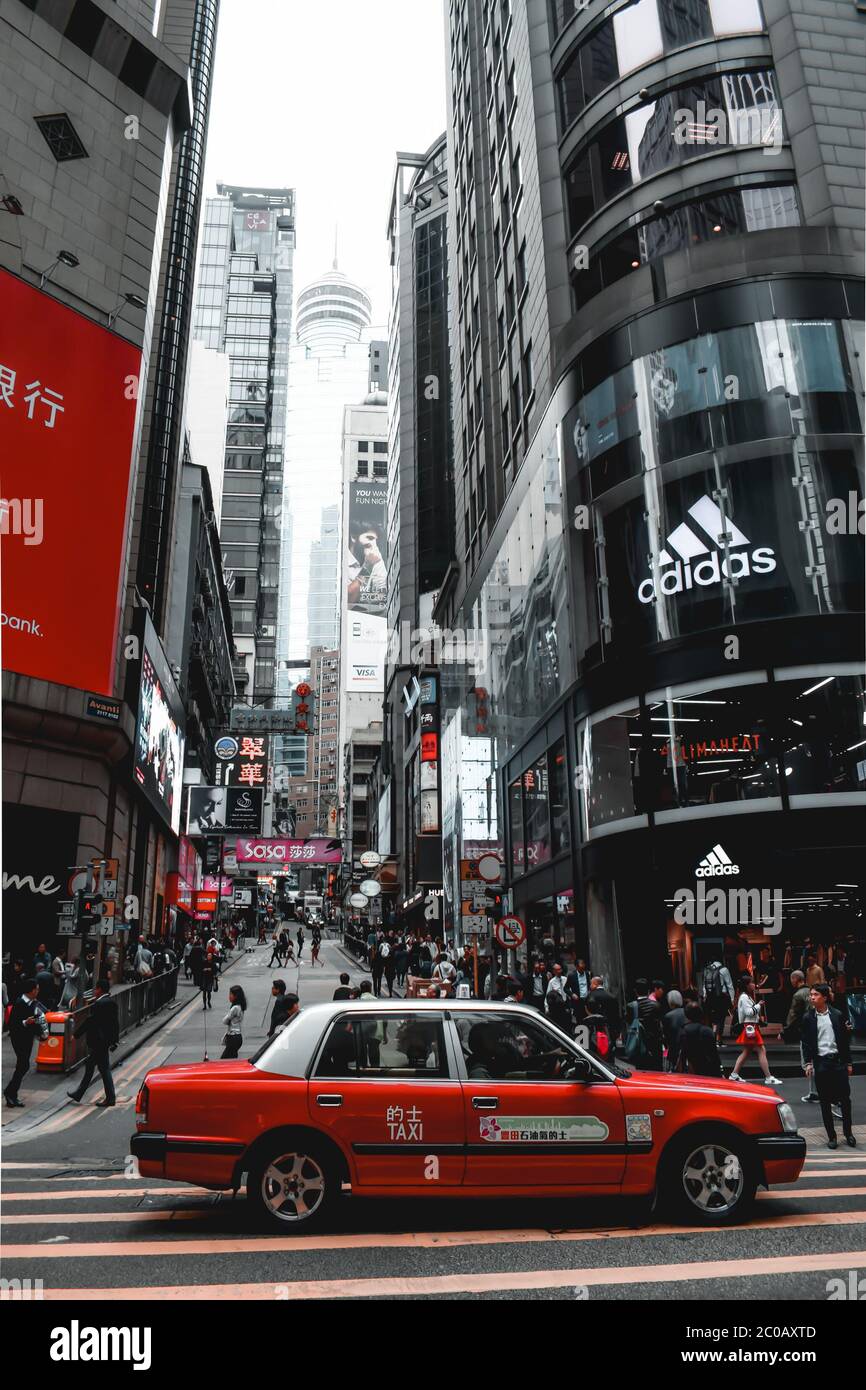 Red taxi waiting on a crosswalk of a luxury shopping street at Hong Kong Island in China Stock Photo