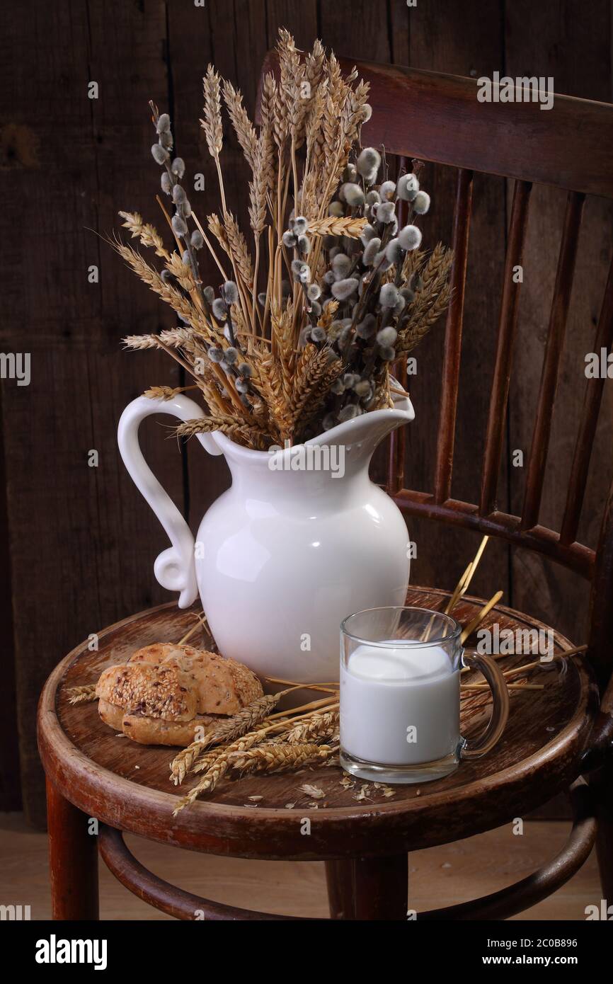 Still-life with milk, fresh bread and a bouquet from cones and a willow Stock Photo
