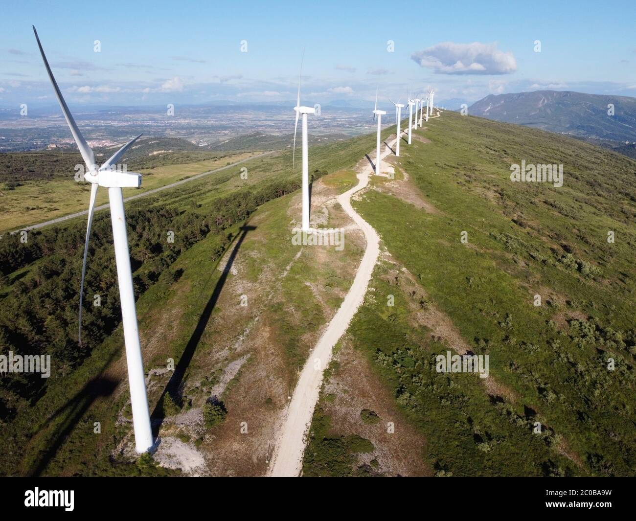 Aerial view of windmills farm for renewable energy production on beautiful blue sky. Wind power turbines generating clean renewable energy for sustainable development. High quality photography. Stock Photo