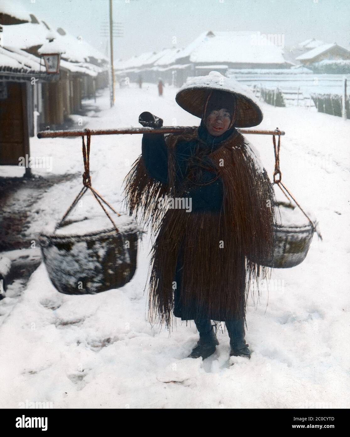 [ 1900s Japan - Japanese Salt Vendor ] — A salt peddler in the snow, wearing a straw raincoat (mino) and carrying a conical hat (菅笠, sugegasa).  20th century vintage glass slide. Stock Photo