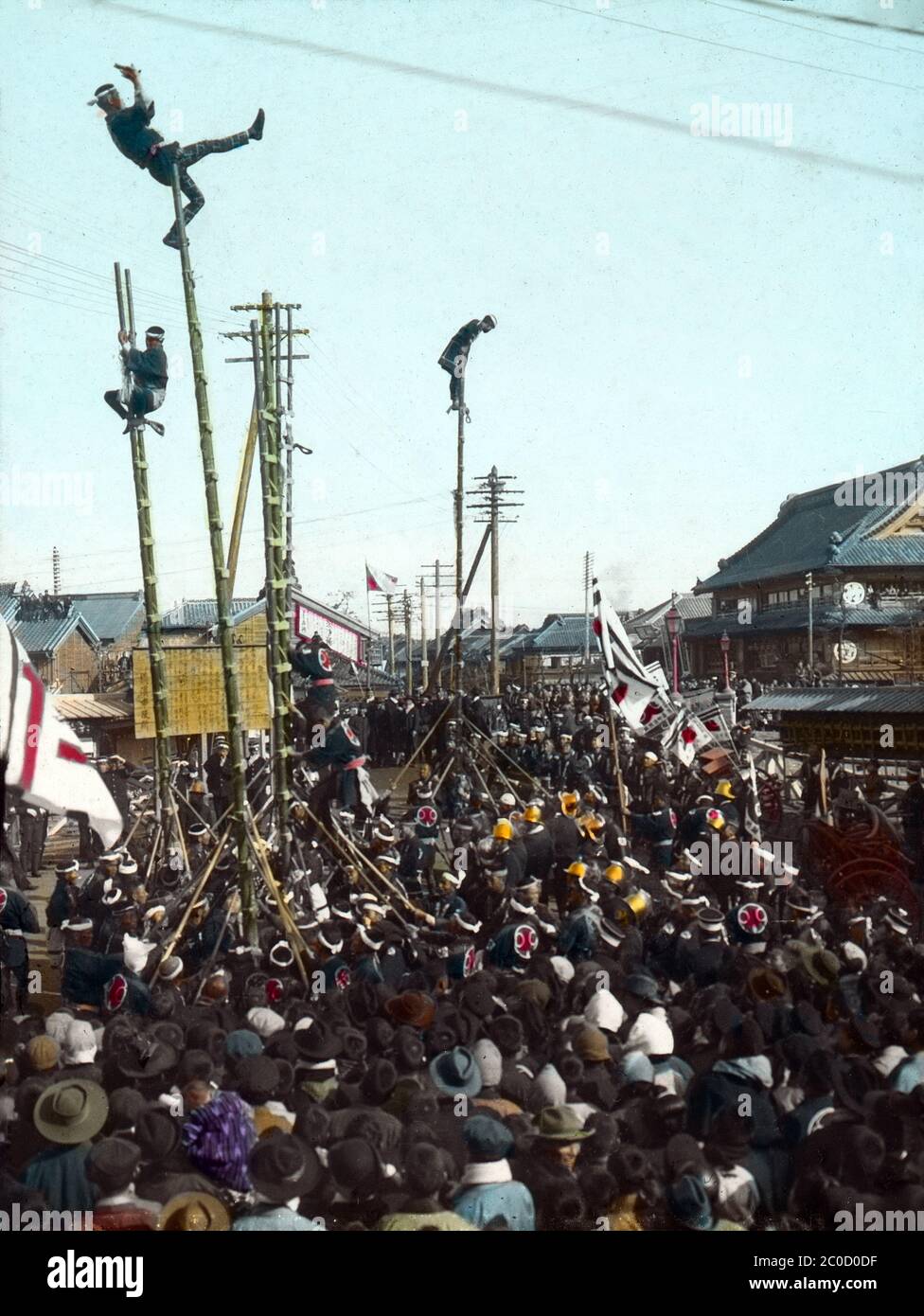 [ 1900s Japan - Japanese Firefighters ] — Firefighters in happi coats perform acrobatic stunts on top of bamboo ladders at Yoshidabashi in Yokohama, Kanagawa Prefecture.  The ladder stunts were the main event of Japanese New Year celebrations.  The demonstrations, called dezome-shiki, were intended to warn people of the dangers of fire, and to demonstrate the agility and courage of the firefighters.  20th century vintage glass slide. Stock Photo