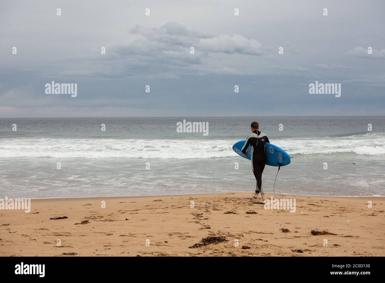 Surf Groms Cloudy Tasmanian Day walking to the water with surf board Stock Photo