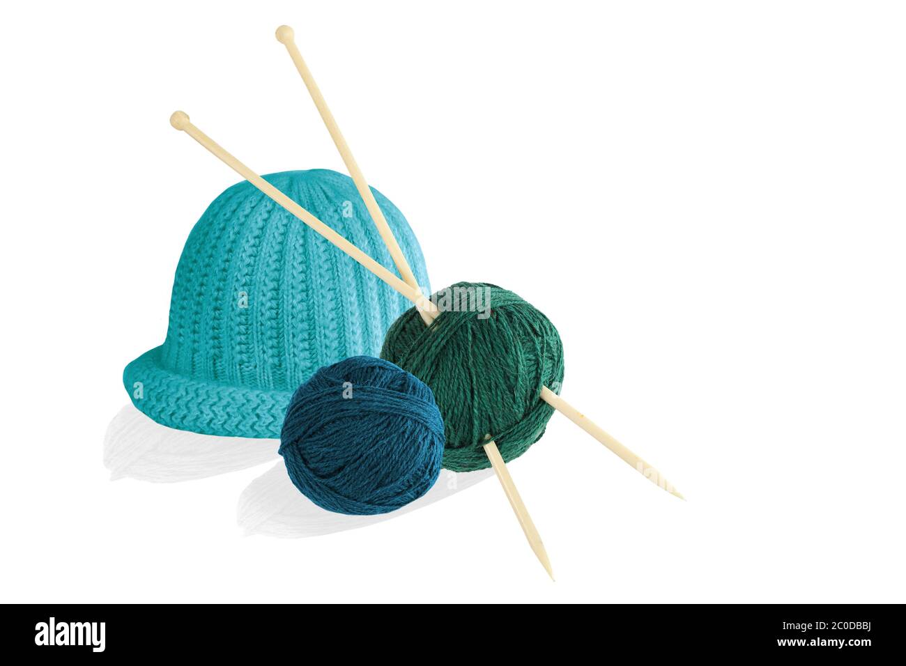 Two balls of wool with knitting needles and cap isolated on white