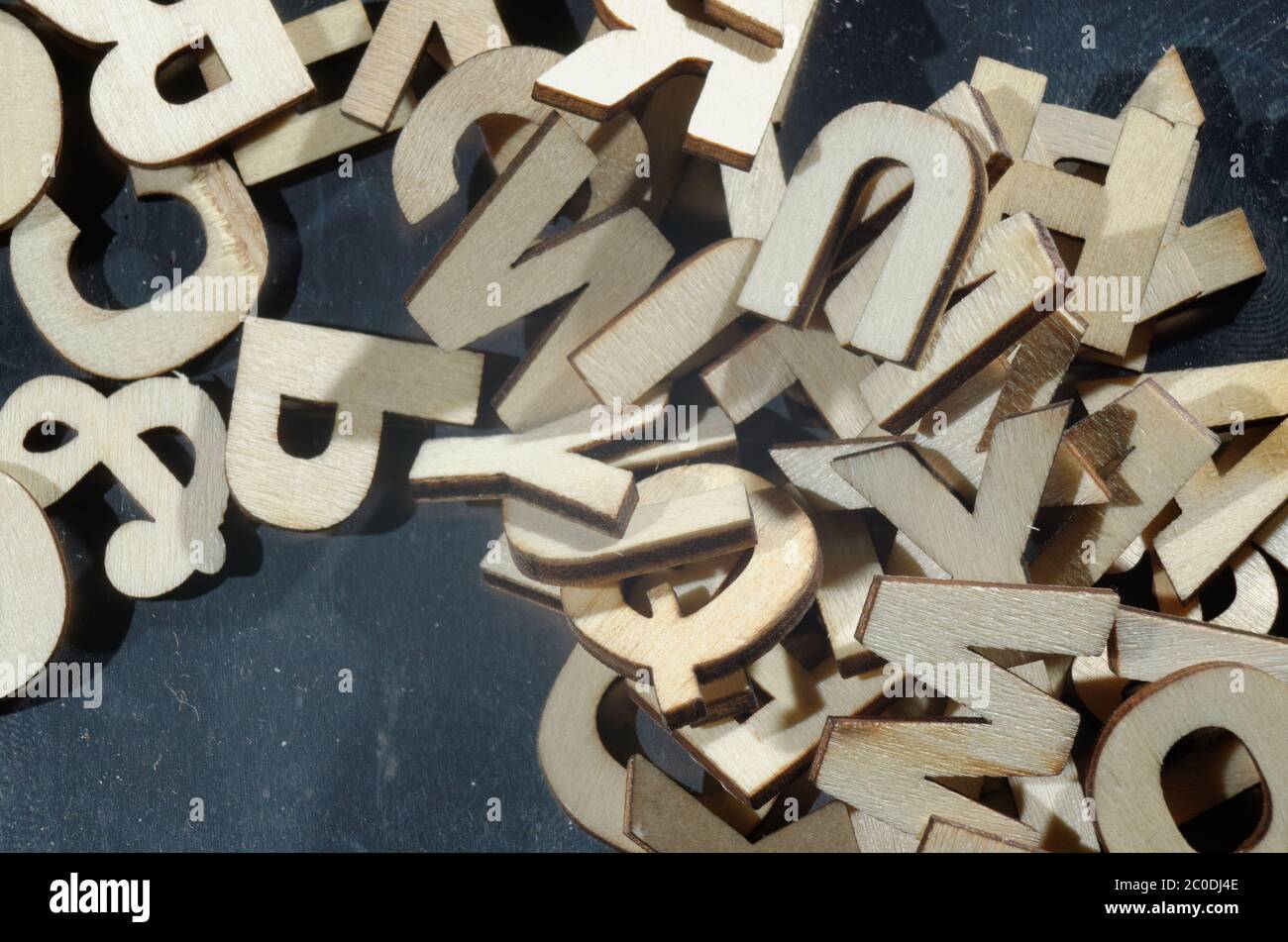 A jumbled pile of wooden letters on a metal surface Stock Photo