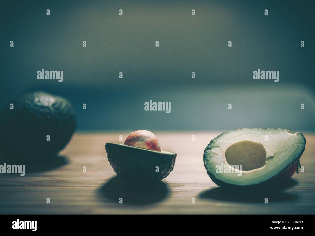 Whole and sliced fresh avocados on wooden table Stock Photo - Alamy