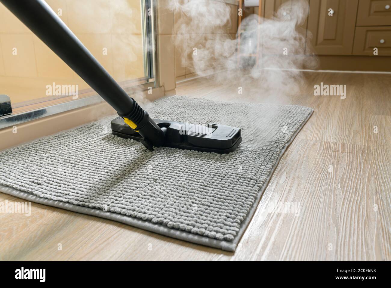 Cleaning bathroom mat using steam cleaner Stock Photo