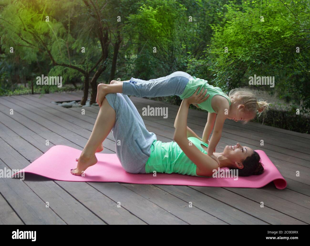 Mother and daughter doing exercise practicing yoga outdoors Stock Photo