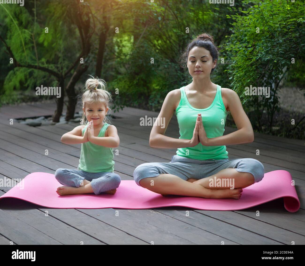 Mother and daughter doing exercise practicing yoga outdoors Stock Photo