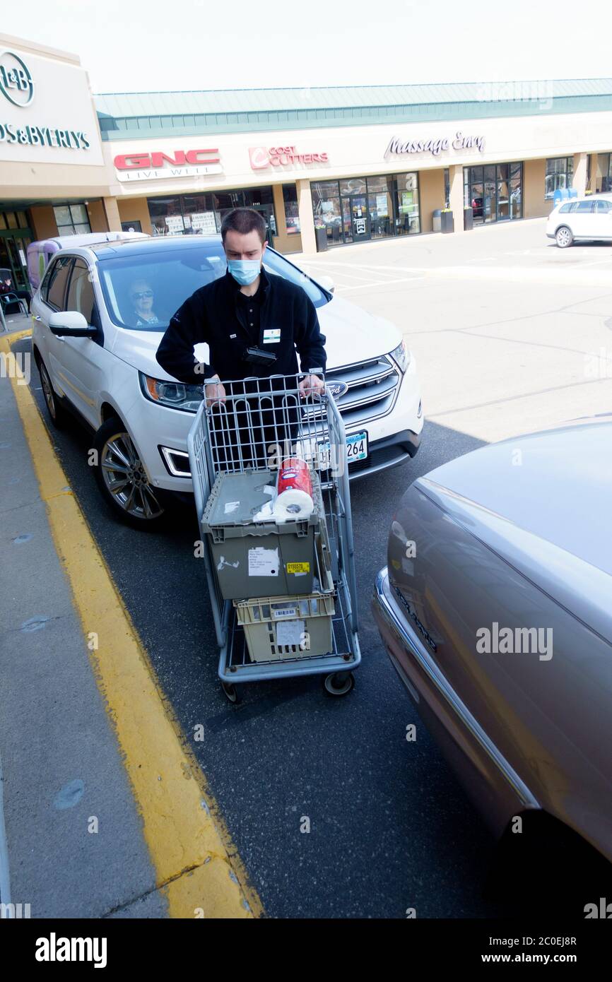 Delivery man pushing cart with groceries to load into car wearing mask & keeping socially distant at Lunds & Byerlys Store. St Paul Minnesota MN USA Stock Photo