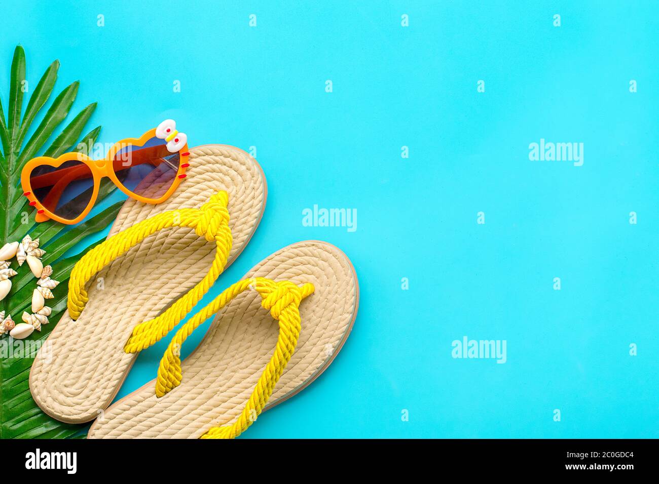 Swimming accessories - sunblock, heart - shaped glasses, yellow flip flop,  palm, shells bracelet isolated on blue background Flat lay Top view Travel  Stock Photo - Alamy