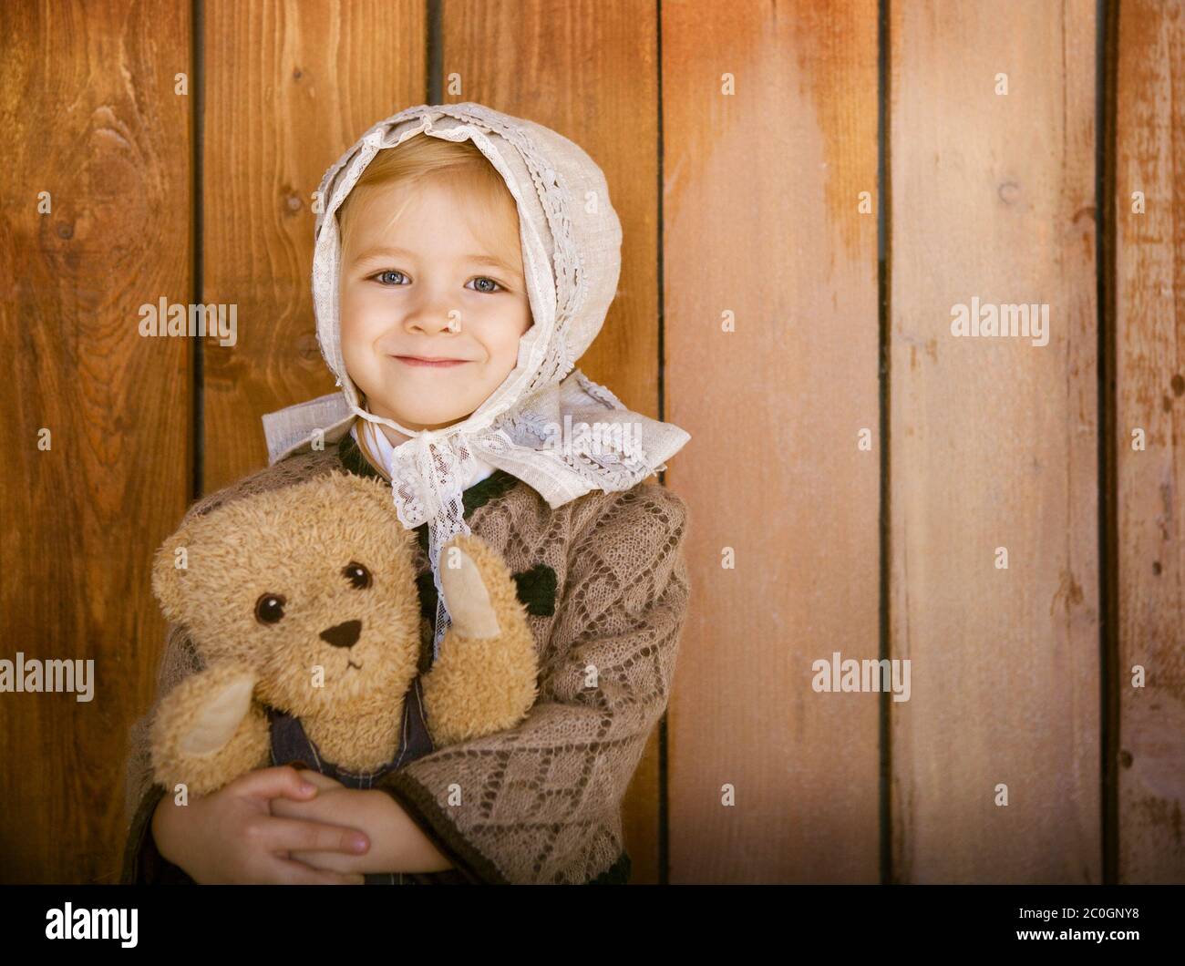 Portrait of the little smiling girl wering vintage clothes with toy bear Stock Photo