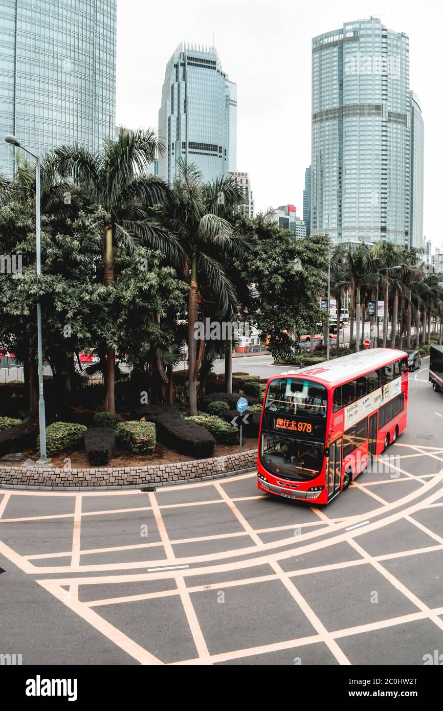 Red double-decker bus passing around palm trees in Hong Kong China Stock Photo