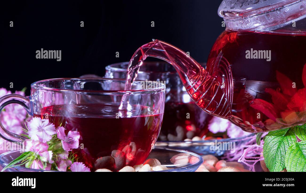 Red tea, hibiscus, karkade, Rooibos. A woman pours tea into a Cup ...