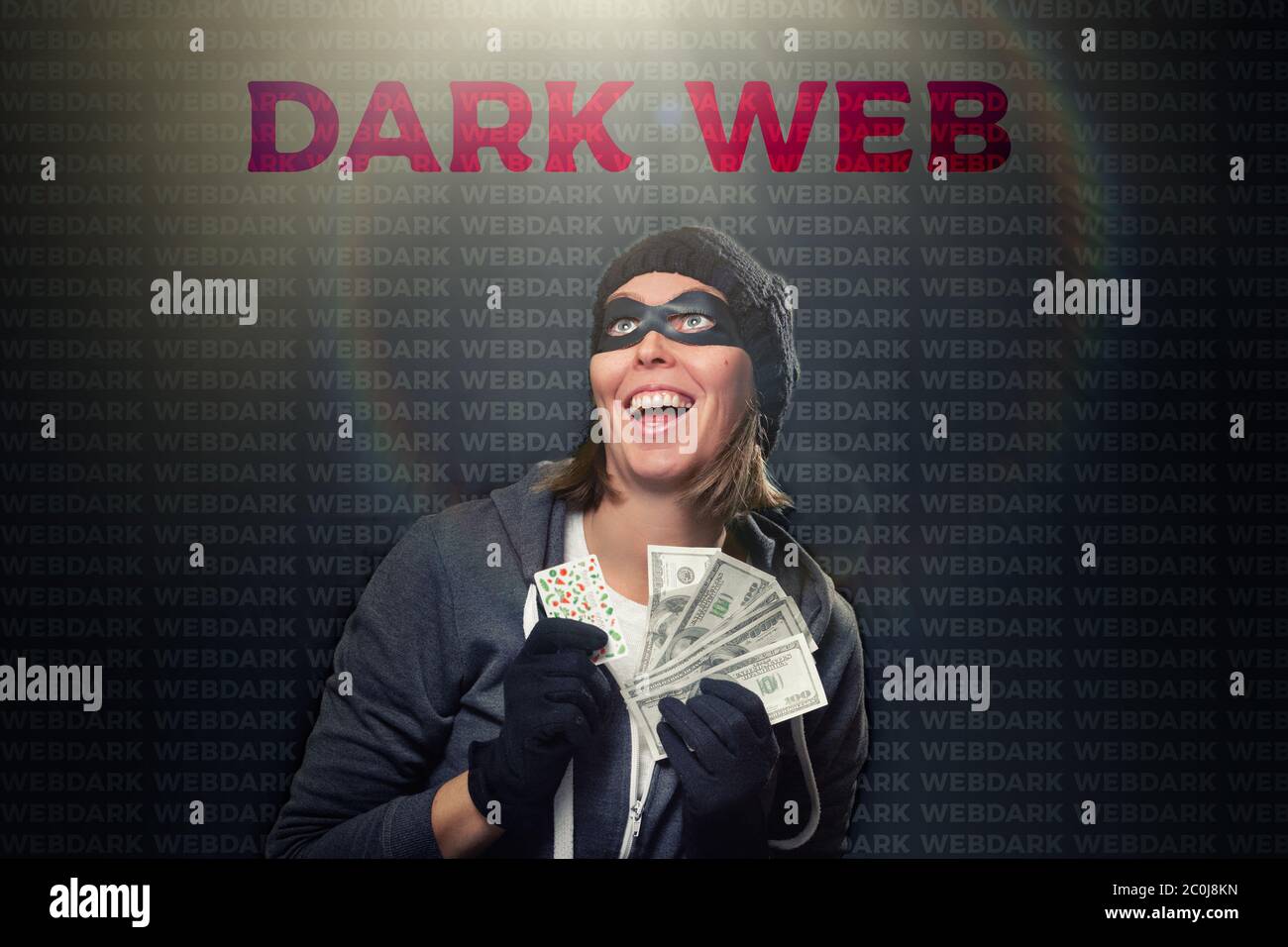 The concept of cybercrime and illegal outlets. Portrait of a woman in a black hat, gloves and mask, who enthusiastically holds a wad of money. Dark ba Stock Photo