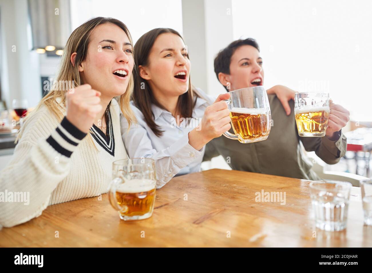 Group of women watch football and drink beer and cheer on their team