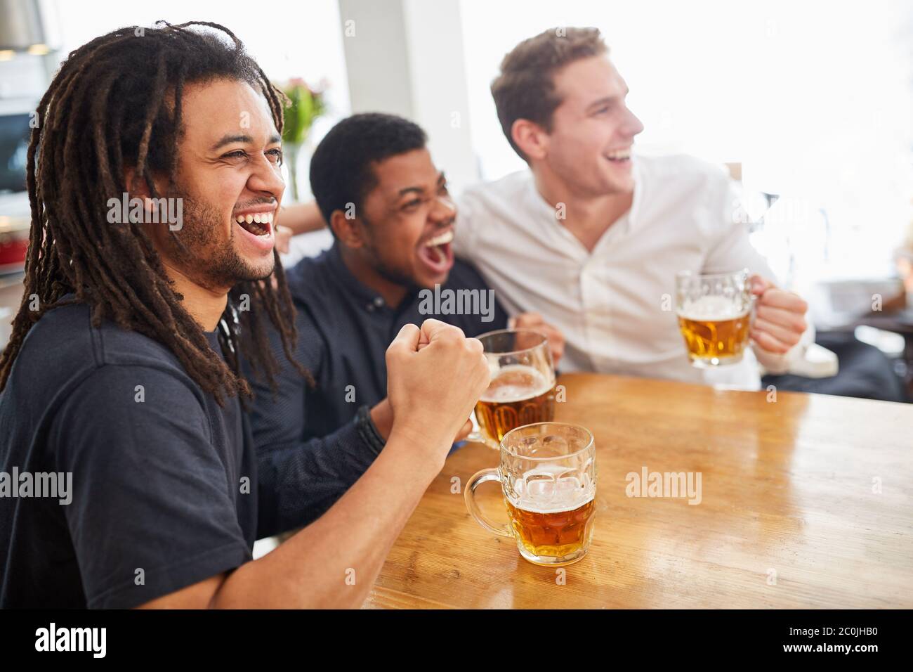 Football fans as spectators cheering on beer at home in front of the television Stock Photo