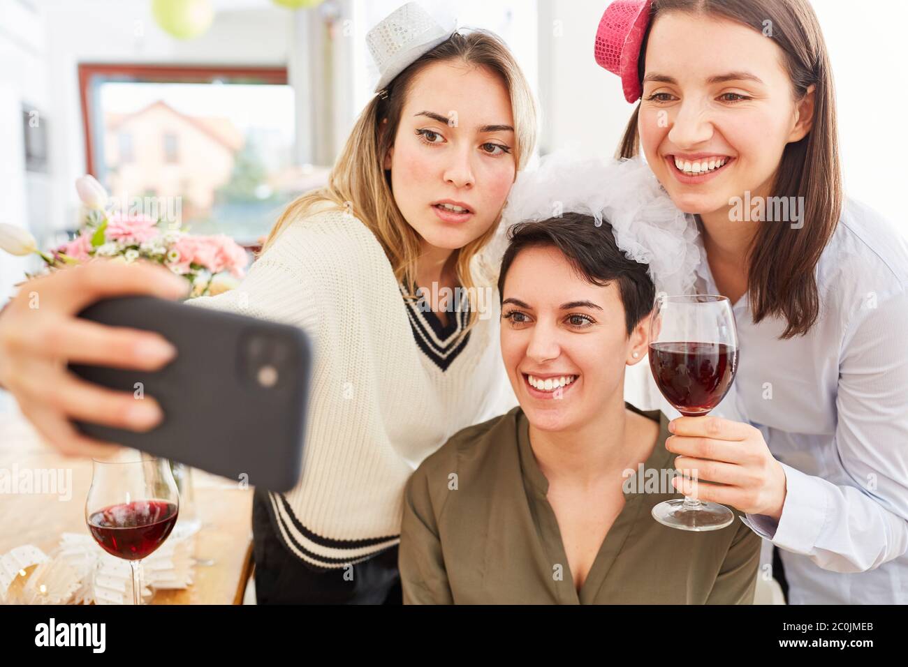 Girlfriends with bride make selfie at hen party at home with glass of ...