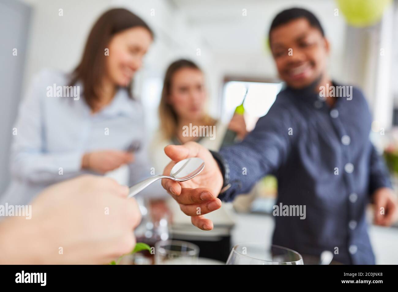 Give the spoon as a saying with friends at the table for a meal together Stock Photo