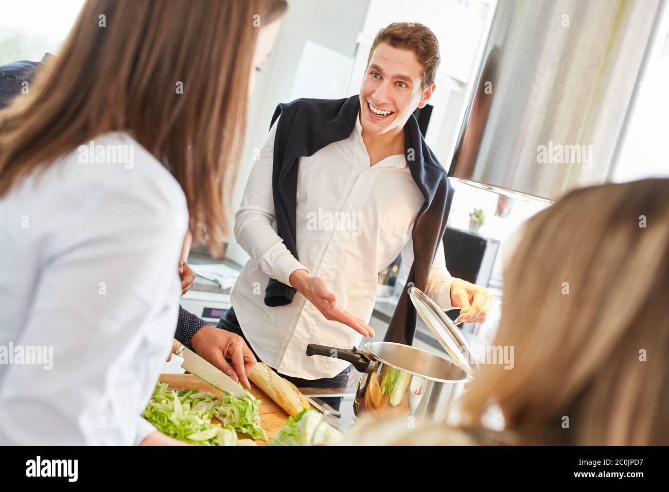 Laughing students prepare meals together in a shared kitchen Stock Photo