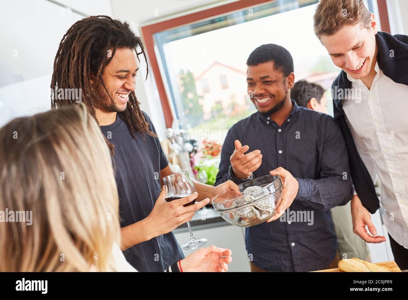 Laughing group of friends drying dishes in the kitchen of a shared apartment Stock Photo