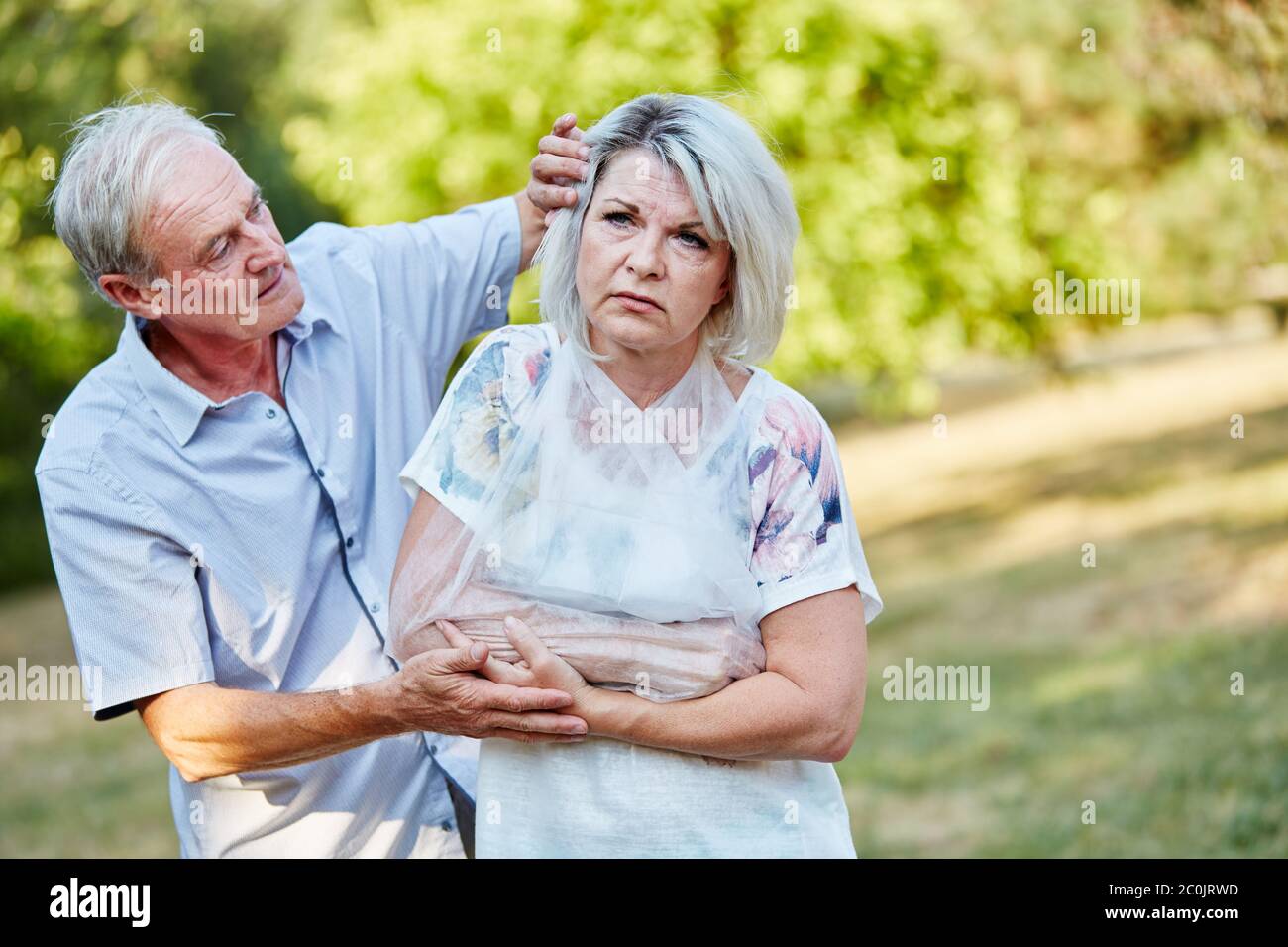 Old woman with a broken arm in a noose in nature Stock Photo