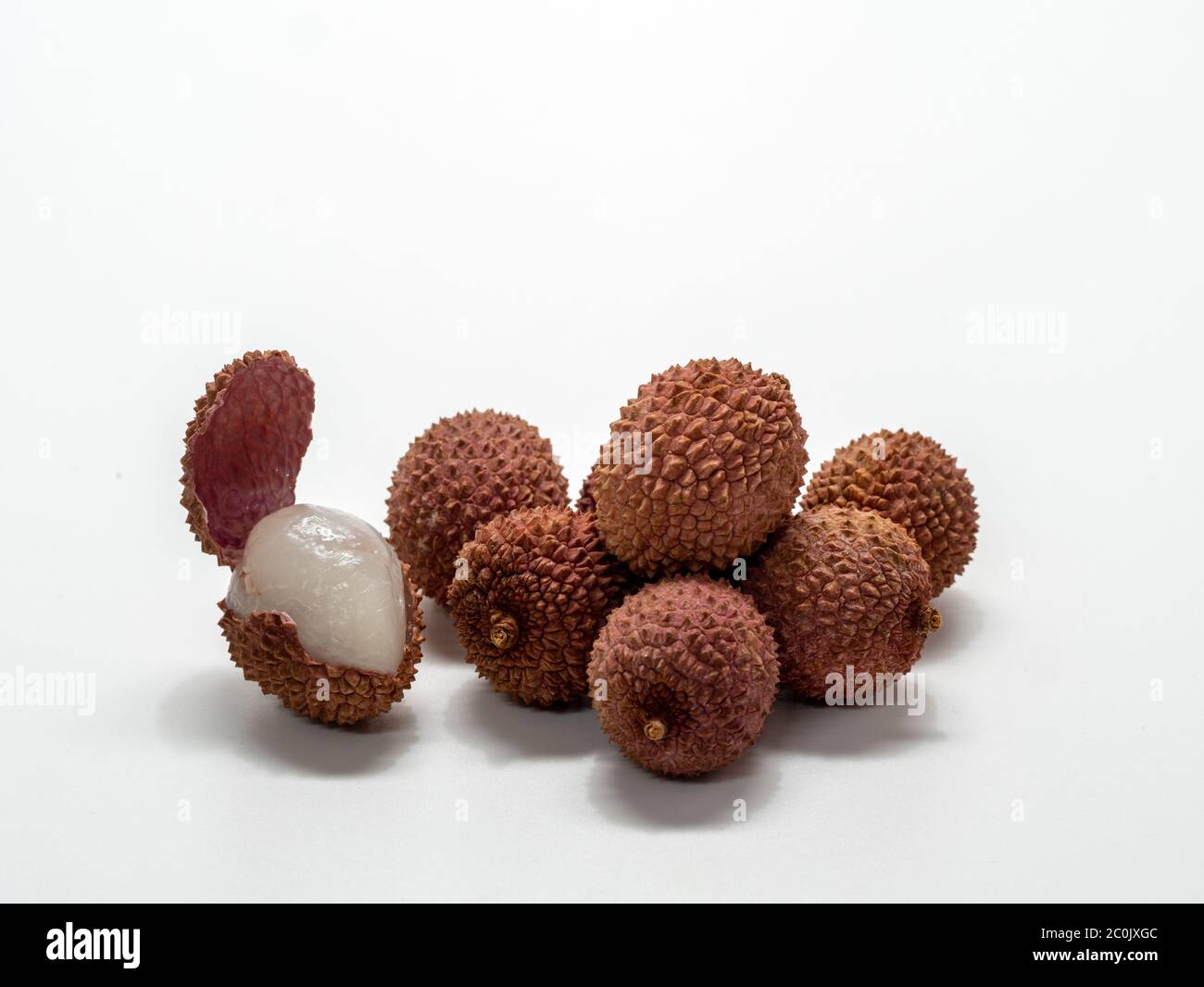 Several lychee fruits, one with open peel. Stock Photo