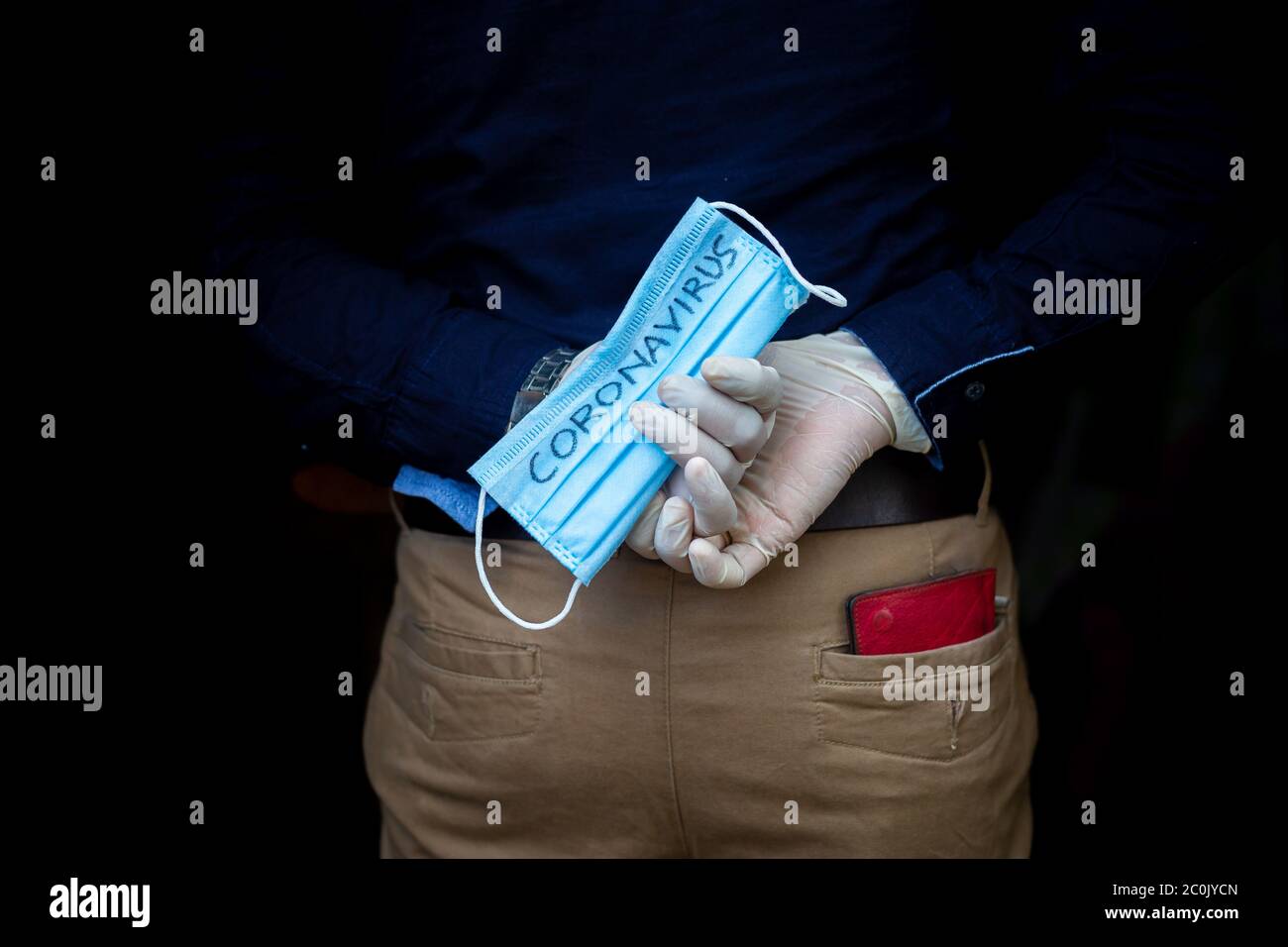 A man stands back holding a surgical mask with his hands wearing ...
