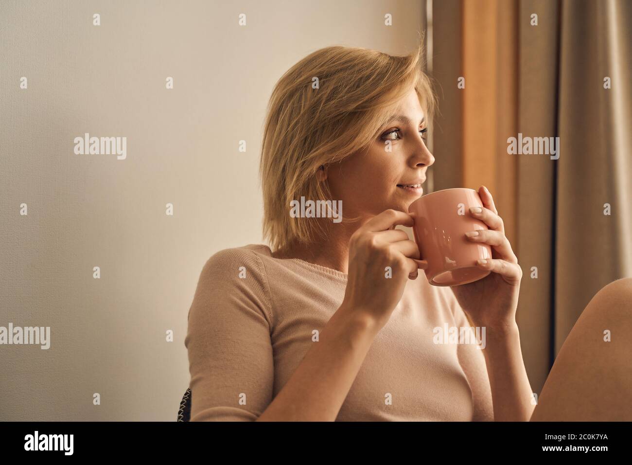 Pleased short-haired lady holding a tea cup Stock Photo