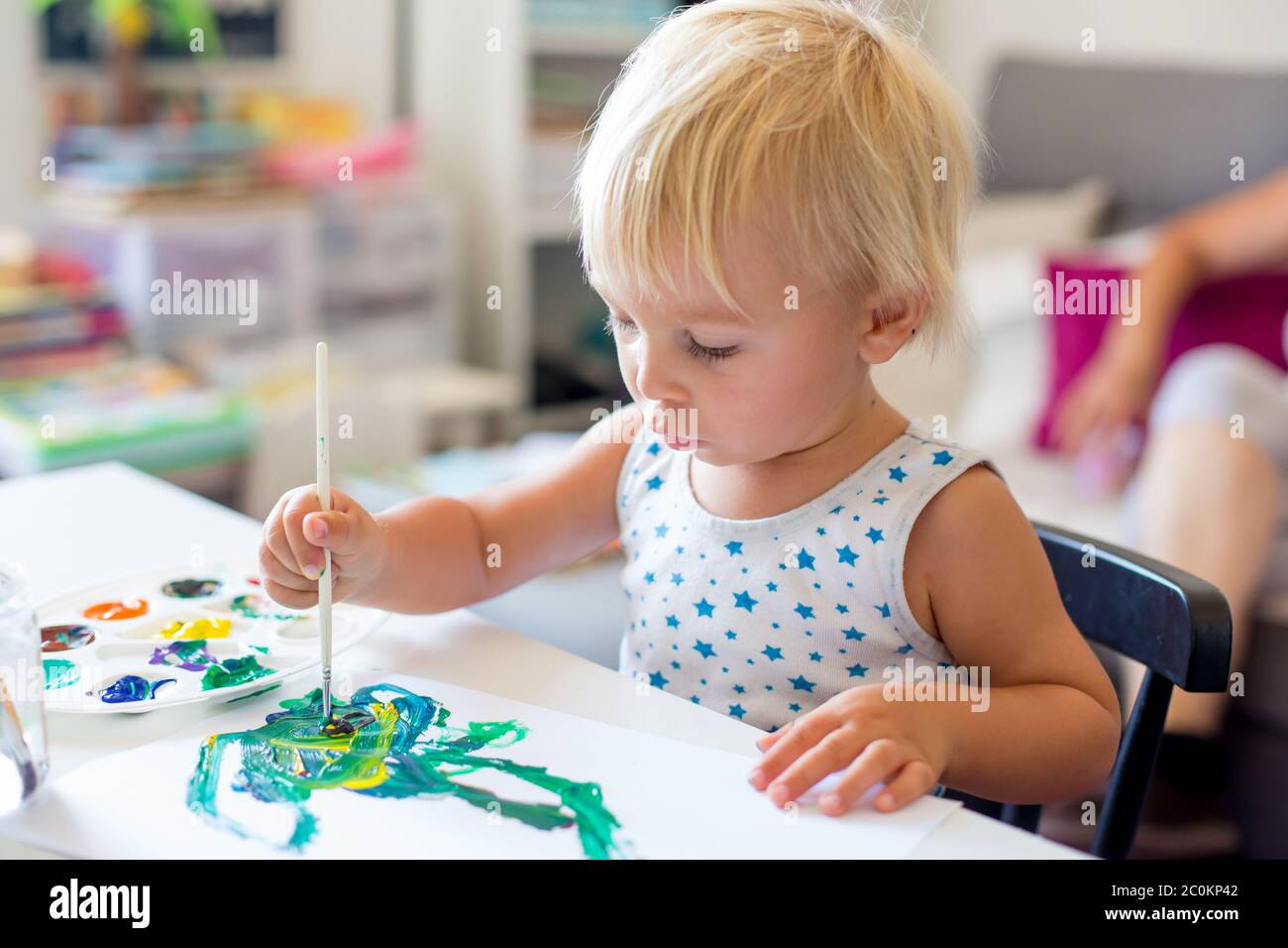 Little toddler boy, painting at home, learning coordination of moves and colors Stock Photo