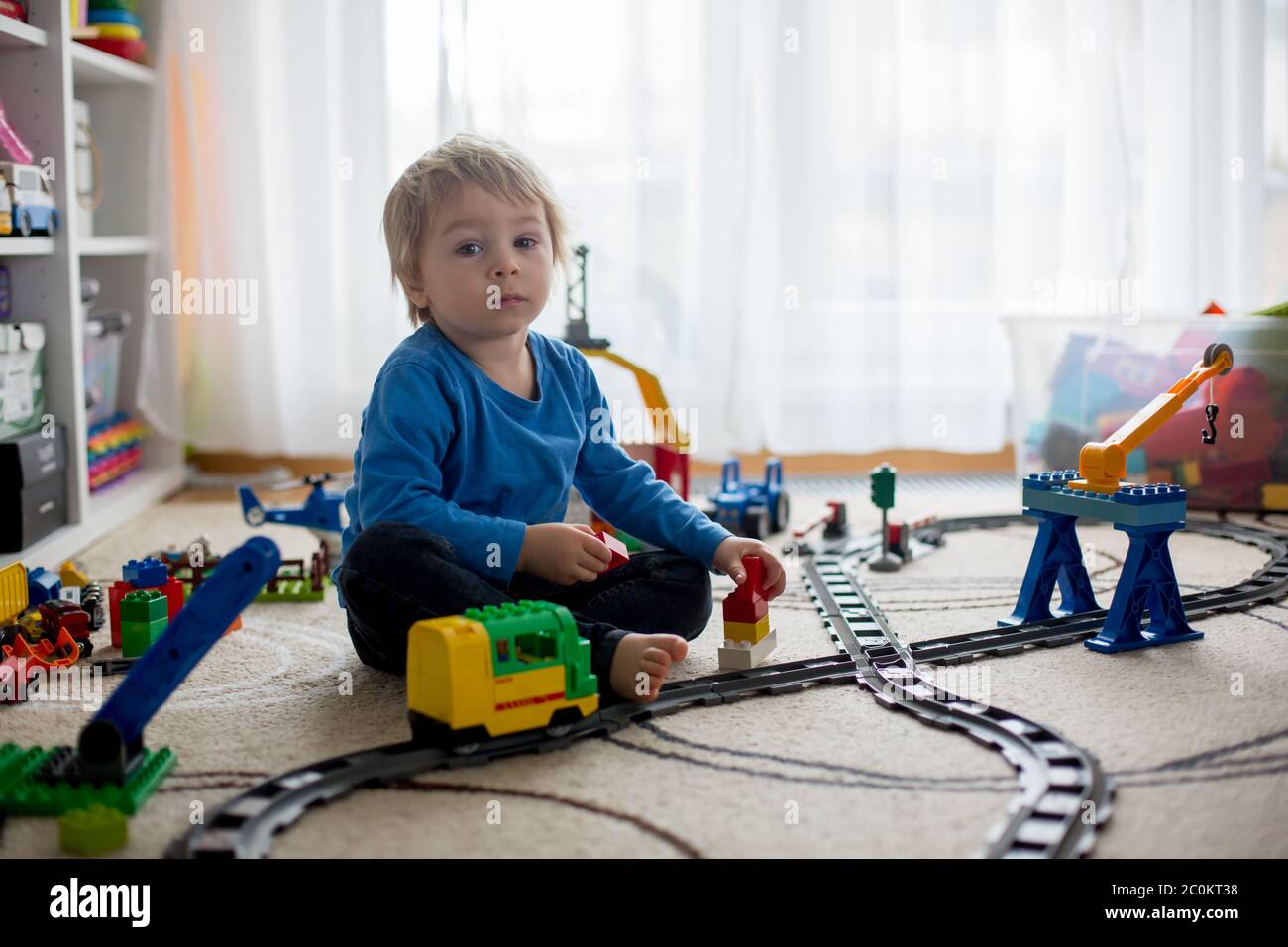 Adorable little boy playing with colorful plastic construction blocks ...