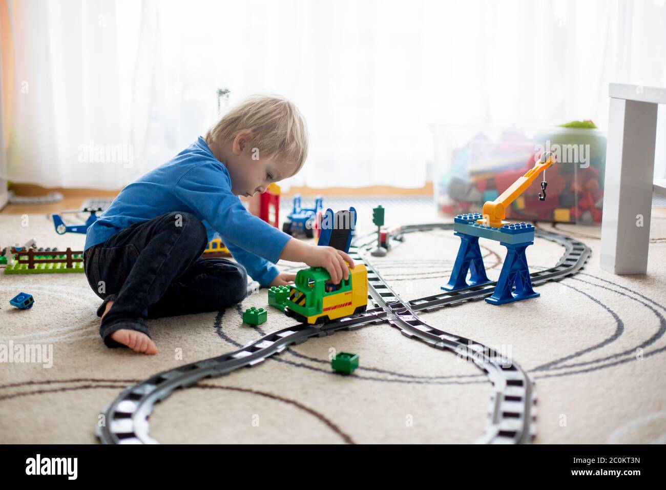 Adorable little boy playing with colorful plastic construction blocks ...