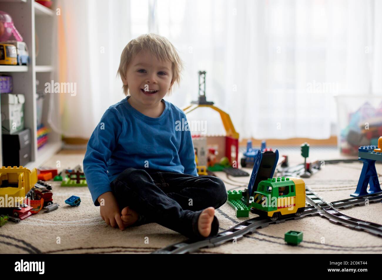 Adorable little boy playing with colorful plastic construction blocks ...